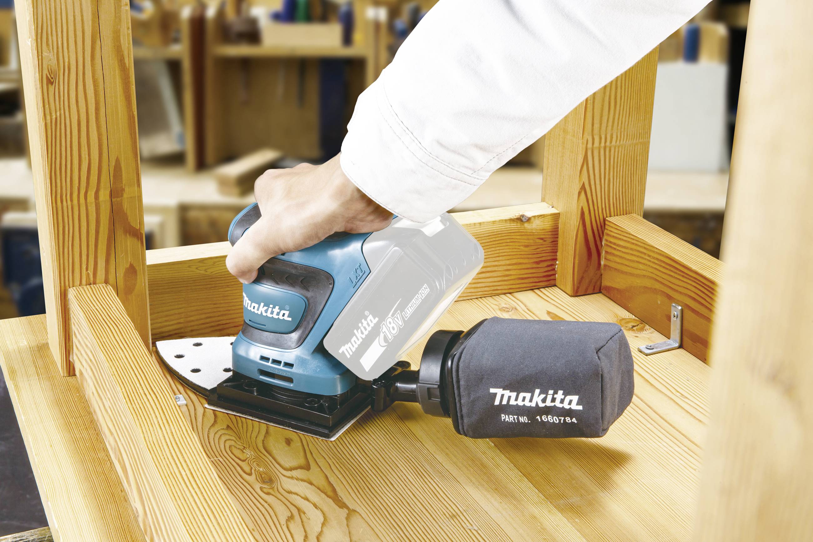 Eine Person schleift eine Holzoberfläche mit einem Makita-Schleifgerät, um die Oberfläche glatt und bearbeitet zu machen.