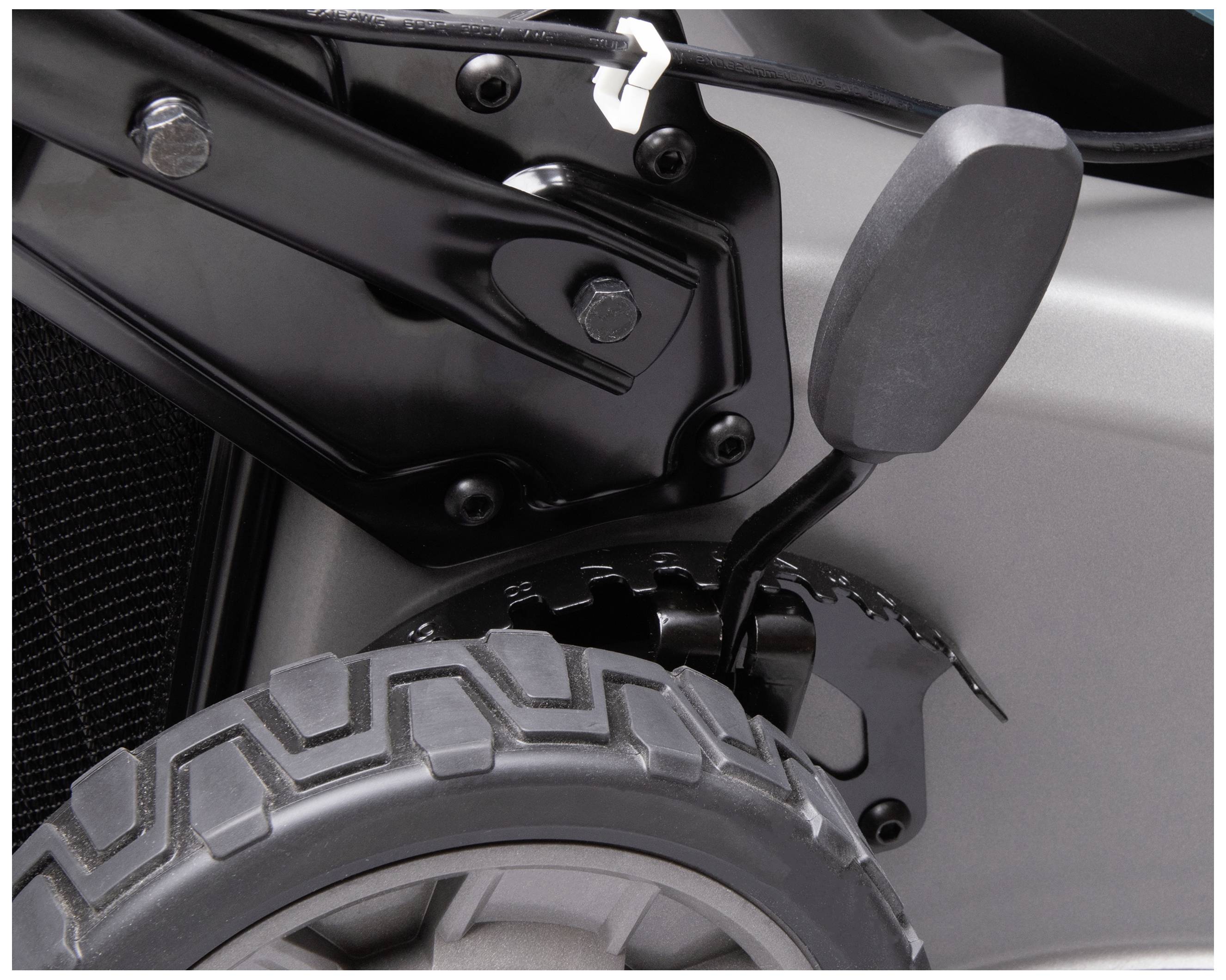 Nahaufnahme eines Teils eines Rollstuhls mit robustem schwarzen Metallrahmen und Profilrad. Sichtbar ist die Verbindung und Verschraubung.