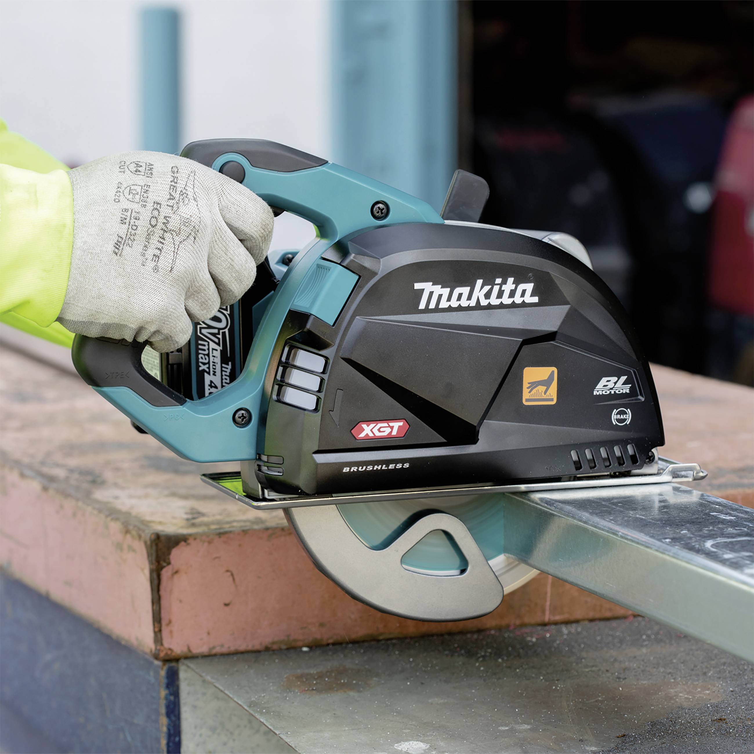 Eine Person hält eine Makita Akku-Handkreissäge, die Holz auf einer Baustelle schneidet. Die Säge hat 'XGT'- und 'BL Motor'-Markierungen.