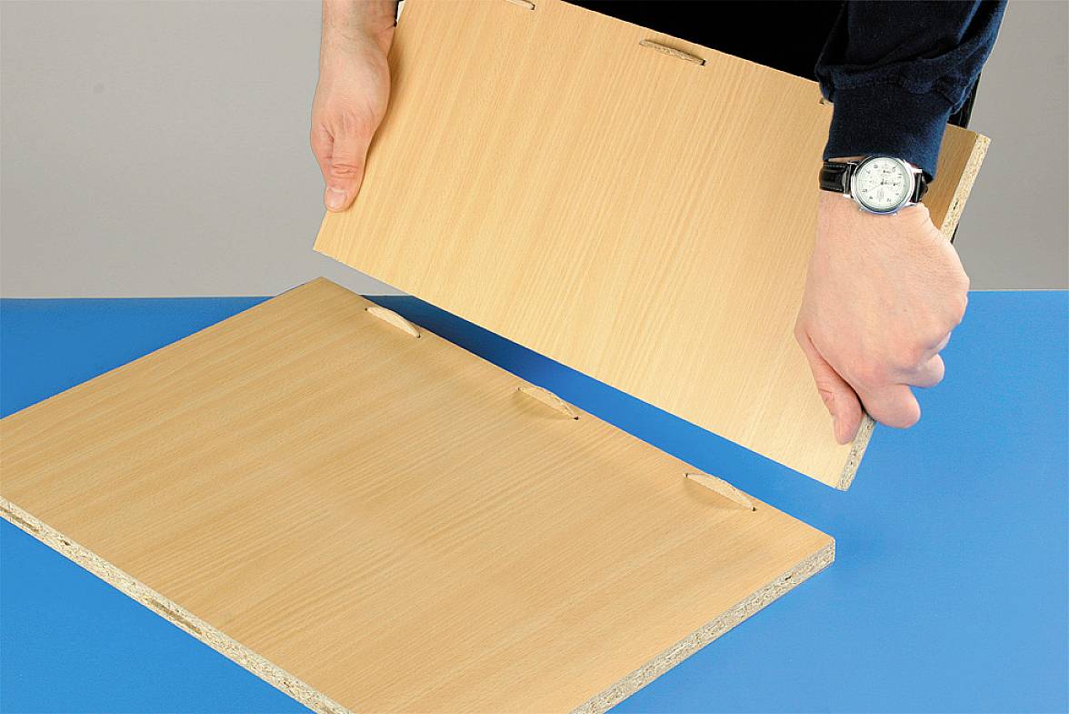 Eine Person montiert zwei Holzplatten mit Nut und Feder. Die Platten werden aneinandergefügt, um eine stabile Verbindung herzustellen.