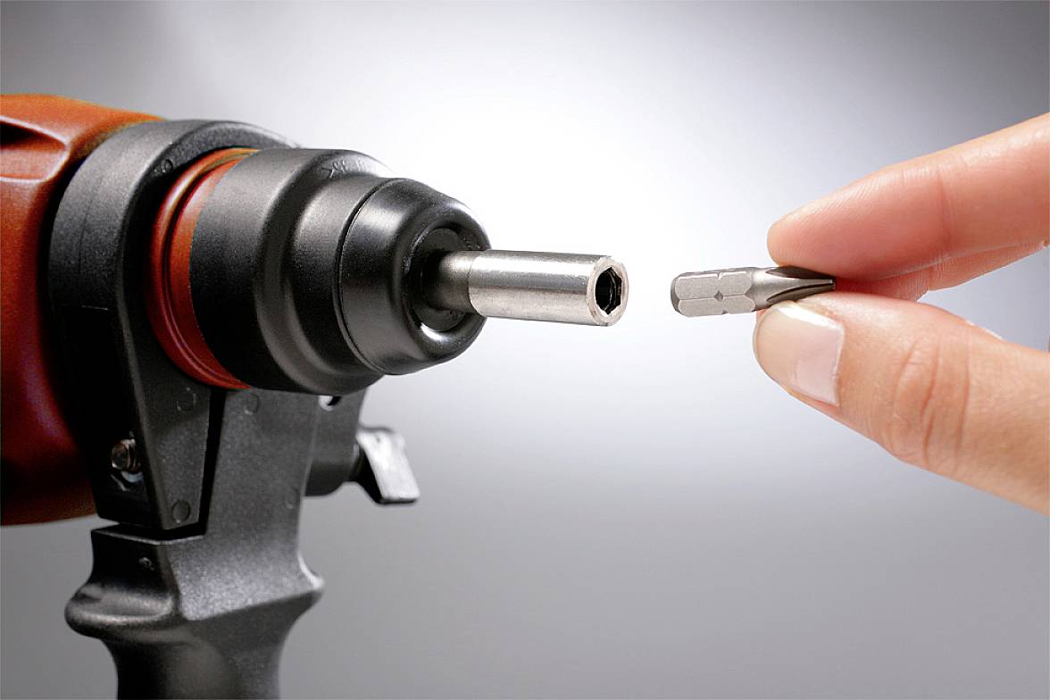 Eine Hand hält einen Schraubendreheraufsatz, der in einen elektrischen Schraubendreher eingesetzt wird.