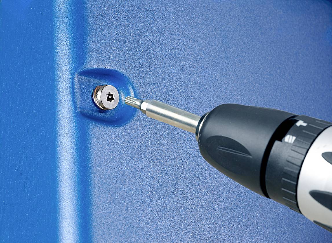 Ein Akkubohrer zieht eine Schraube in eine blaue Oberfläche ein.