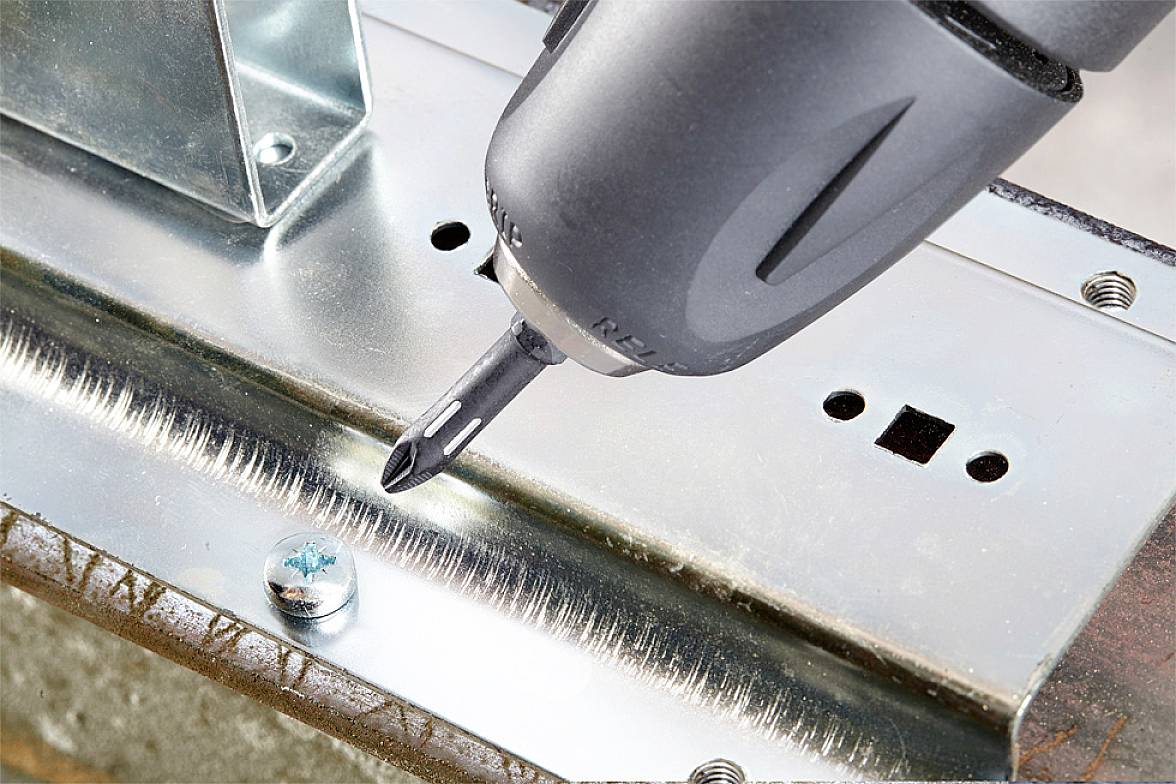 'Elektrischer Schraubendreher zieht Schraube ein.' Ein elektrowerkzeug wird verwendet, um präzise eine Schraube in ein Metallstück zu schrauben.
