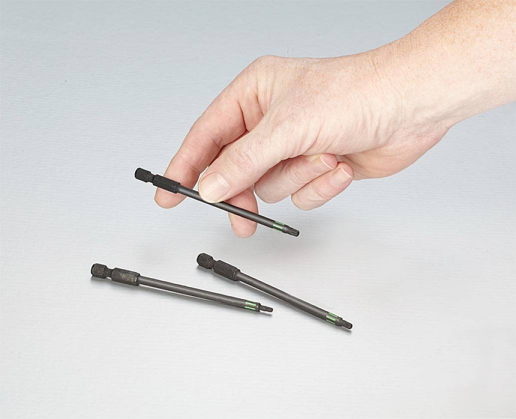 Eine Hand hält einen Magnet-Bithalter, während drei weitere Bithalter auf einer Oberfläche liegen.