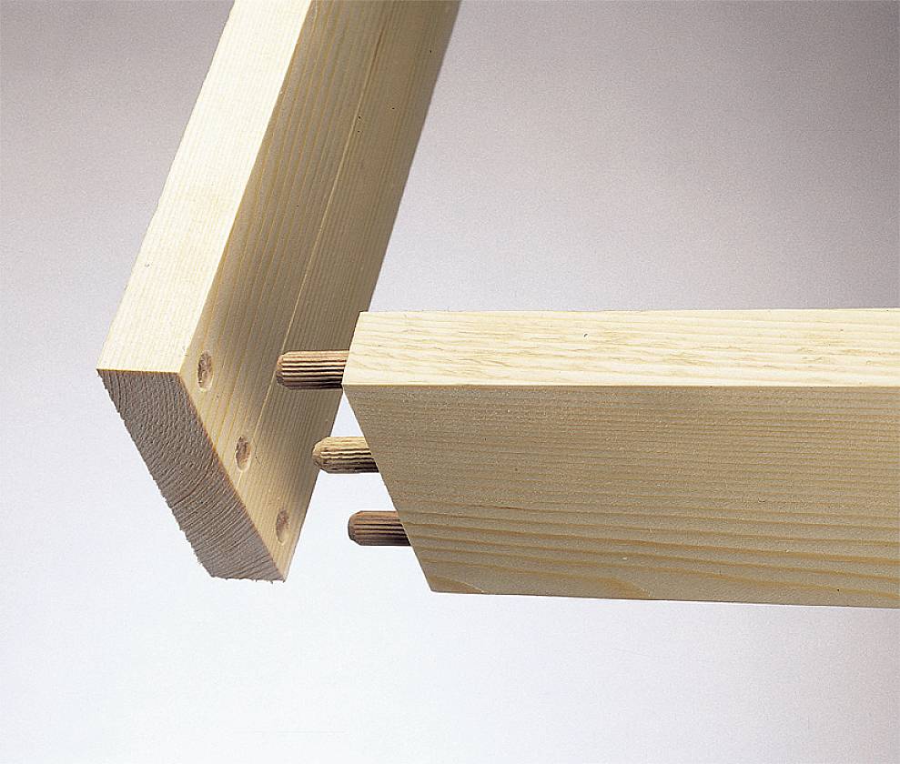 Zwei Holzbretter werden durch Holzdübel miteinander verbunden. Die Bretter sind aus hellem Holz und werden im rechten Winkel zusammengefügt.