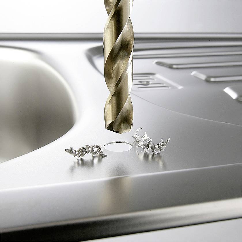 Bohrer durchbohrt Metalloberfläche mit Metallspänen um das Loch.