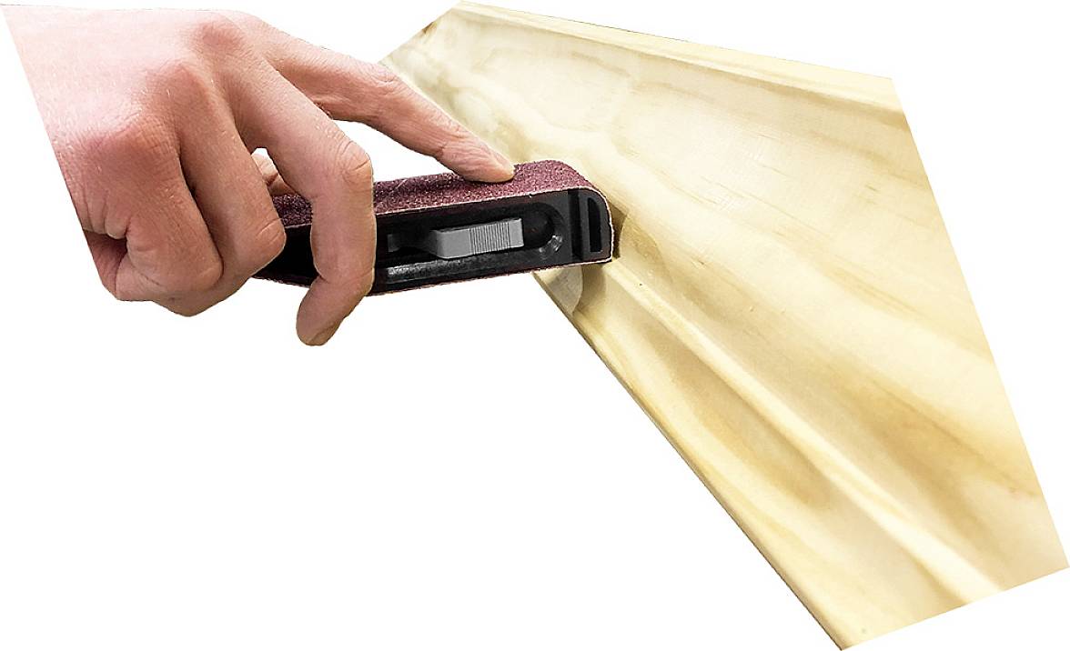 Eine Hand hält ein Schleifwerkzeug und bearbeitet die Kante eines Holzstücks.