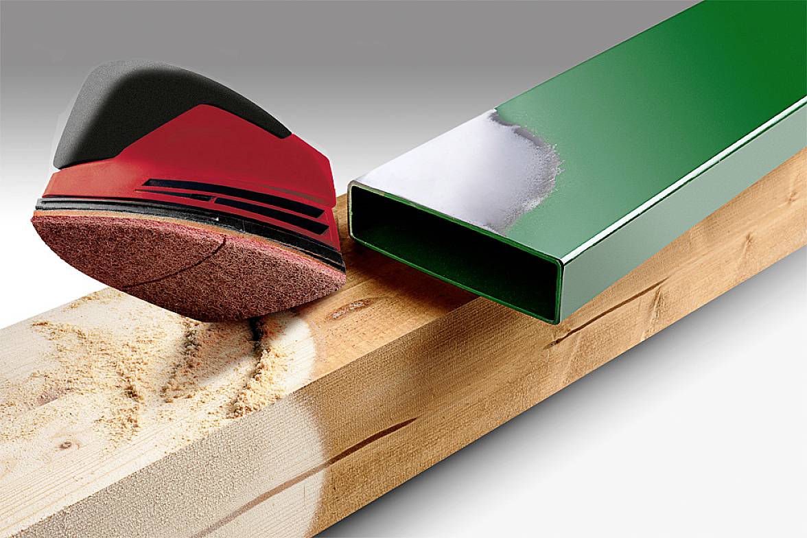 Ein rotes Schleifgerät schleift eine Holzfläche. Daneben ein grünes, rechteckiges Metallrohr mit glatter Oberfläche.