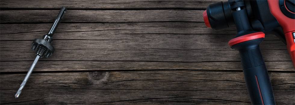 Akkubohrmaschine mit rotem Griff liegt auf einem Holztisch; daneben ein Schraubbohreraufsatz.