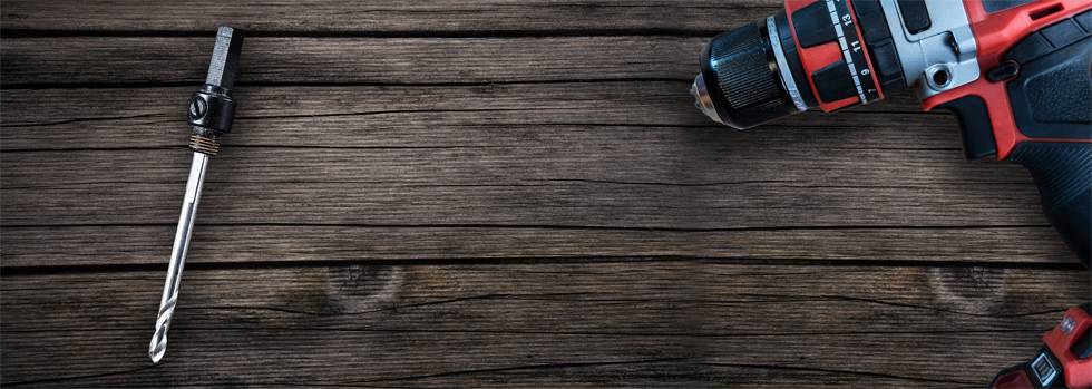Akkubohrmaschine und Bohrkopf liegen auf Holzoberfläche. Links Bohrkopf, rechts die Maschine. Werkzeug zum Heimwerken.
