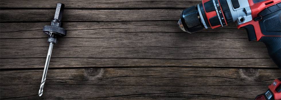 Akkuschrauber mit Bohrer auf Holzhintergrund. Links ein Einsatzbohrer, rechts der Schrauber. Fokus auf Werkzeugausrüstung.