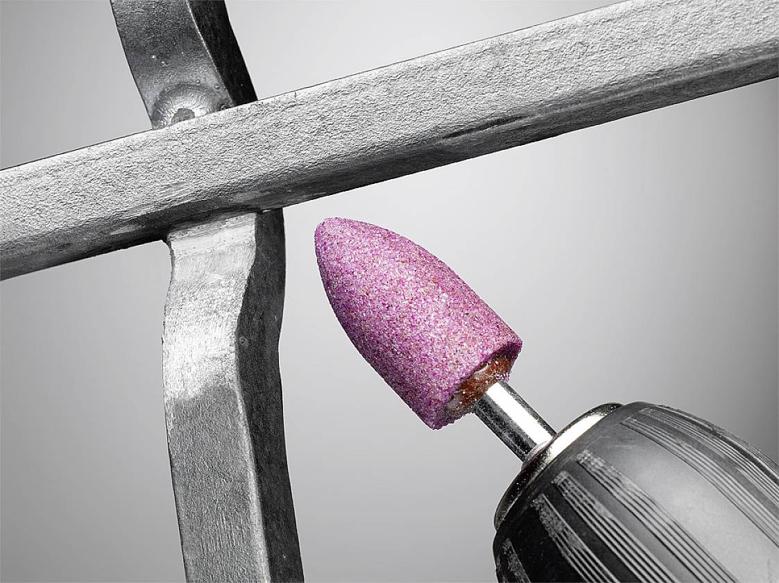 Ein Schleifaufsatz poliert die raue Oberfläche eines Metallgitters.