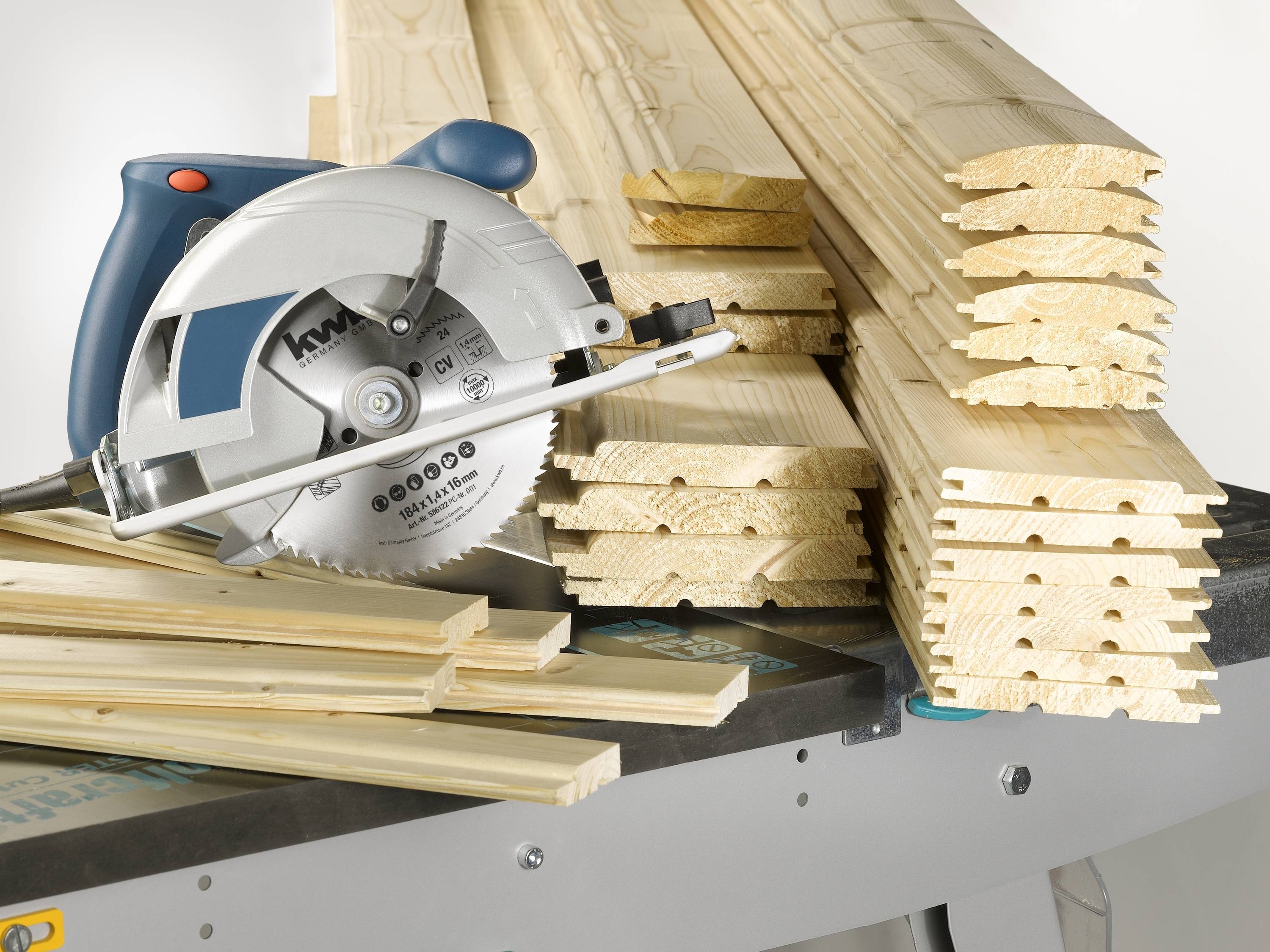 Eine Kreissäge liegt neben einem Stapel Holzlatten auf einer Werkbank, bereit für Holzarbeiten.