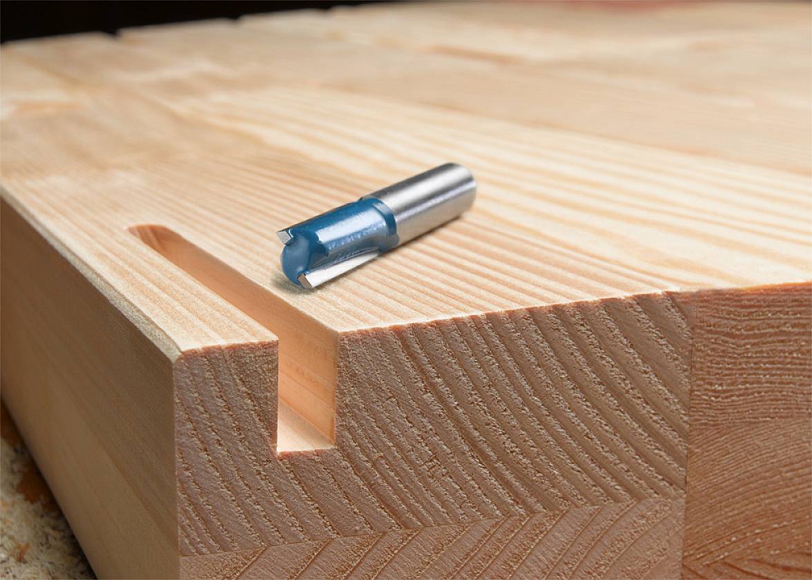 Ein Fräskopf liegt auf einem massiven Holzblock mit einer eingefrästen Nut.