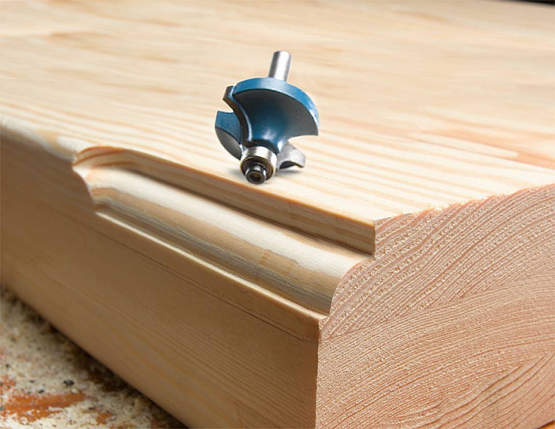 Ein Fräser über einem Stück Holz, um eine dekorative Kante mit einem Profil zu gestalten. Das Holz zeigt frische Schnittkanten.