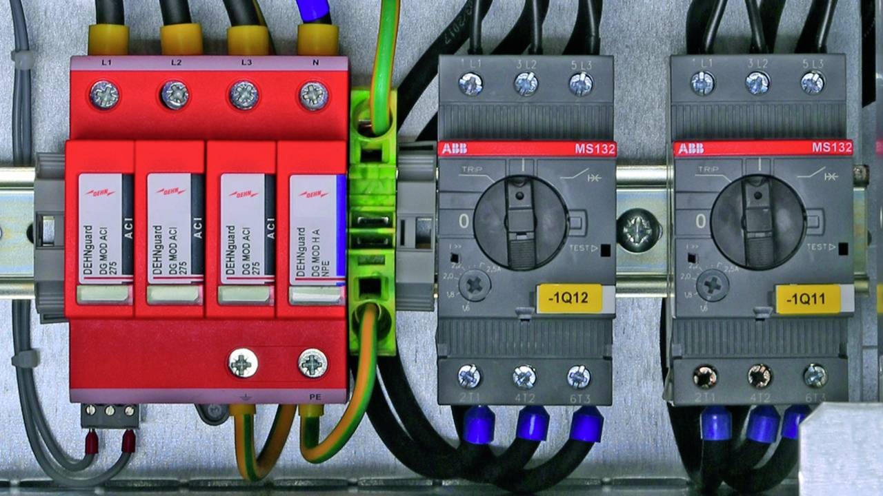 Ein Schaltschrank mit mehreren Schaltern und Sicherungen, darunter rote und graue Module, die elektrische Verbindungen verwalten.