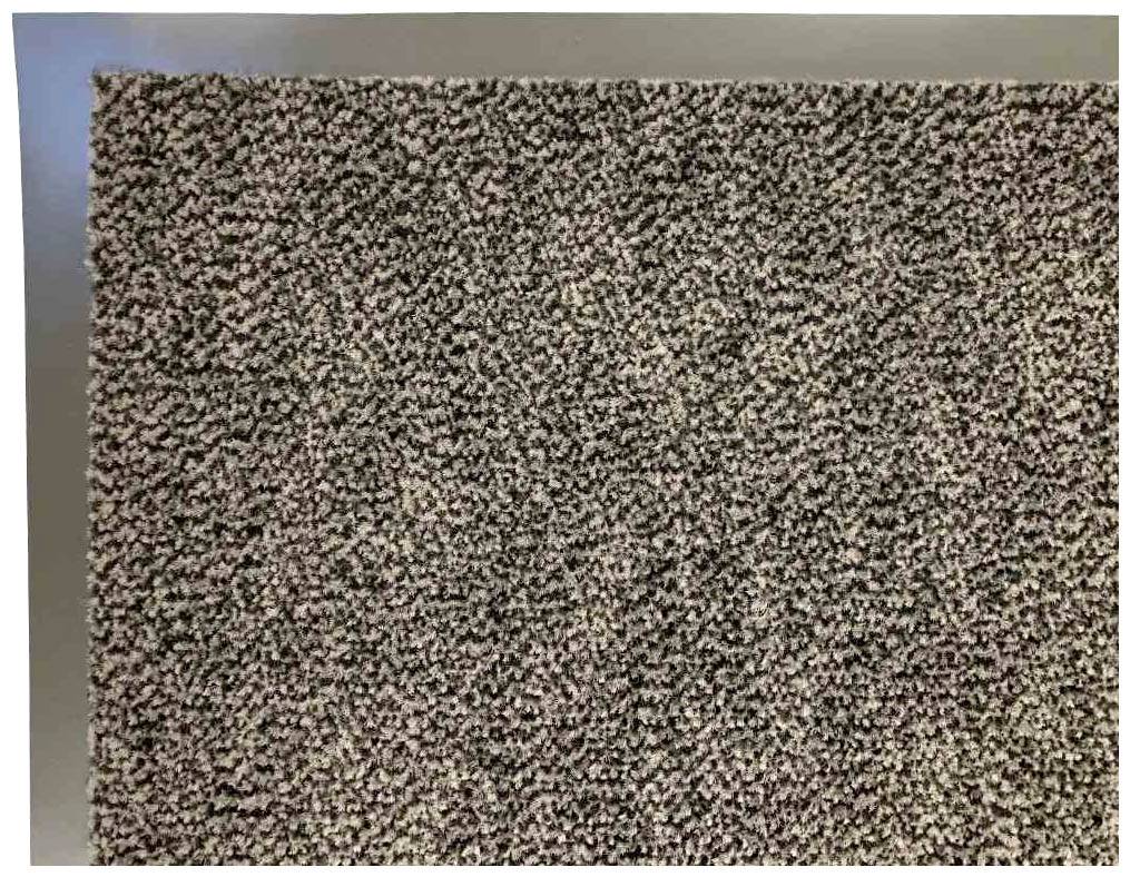 Grauer, grob strukturierter Teppich aus Nahaufnahme. Der Teppich hat eine gleichmäßige, körnige Oberfläche mit gemischten Grautönen.