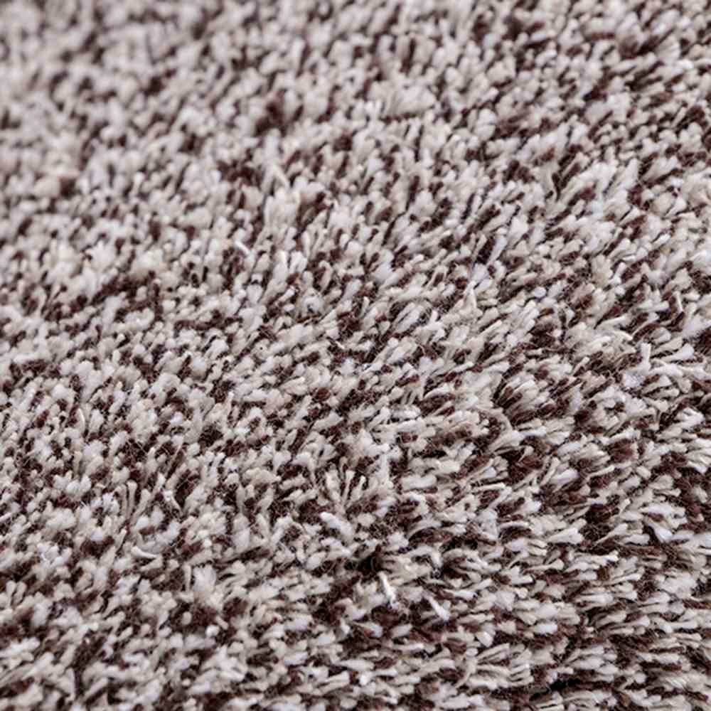 Nahaufnahme einer flauschigen beige-braunen Teppichoberfläche mit dichter Fasernstruktur.