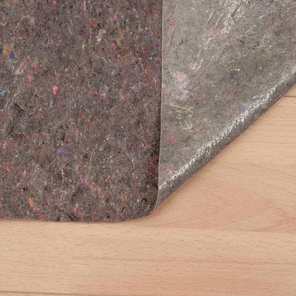 Eine Teppichunterlage auf einem Holzboden zeigt eine Schicht aus grauem, texturiertem Material und eine schützende, transparente Folie.