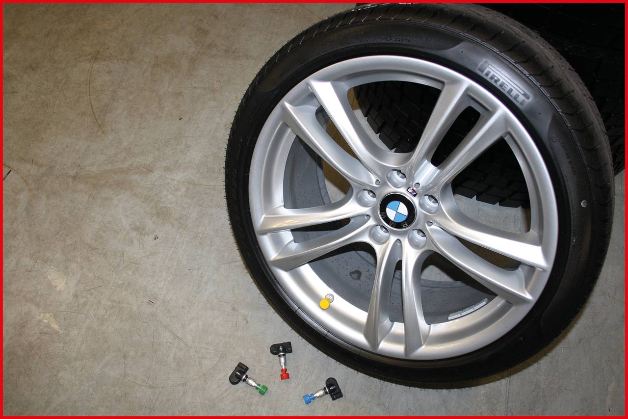Ein silbernes Autoreifenrad mit BMW-Logo liegt auf dem Boden. Daneben liegen kleine bunte Objekte.