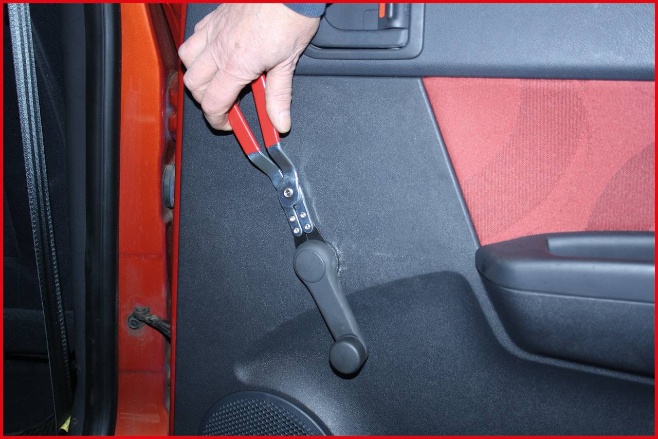 Eine Person benutzt ein Spezialwerkzeug, um eine manuelle Fensterkurbel im Auto zu entfernen.