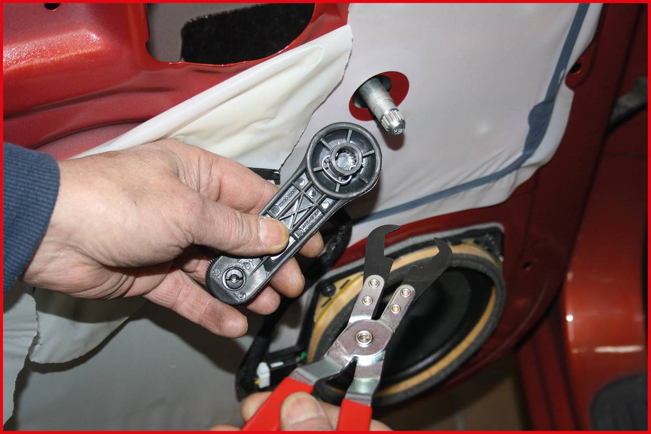 Eine Person hält ein Autotür-Teil und eine Spezialzange, offenbar bei der Reparatur eines Fahrzeugs.