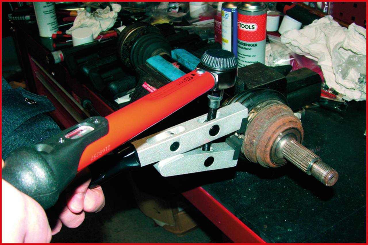 Eine Person benutzt ein Werkzeug, um eine Lenkstange auf einer Werkbank zu bearbeiten. Im Hintergrund sind Werkzeug und Zubehör zu sehen.