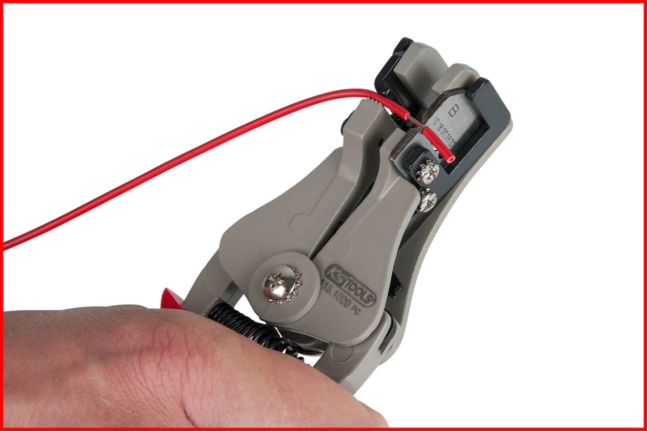 Hand hält graue Kabelzange, die ein rotes Kabel abisoliert. Detailaufnahme des Abisolierprozesses.