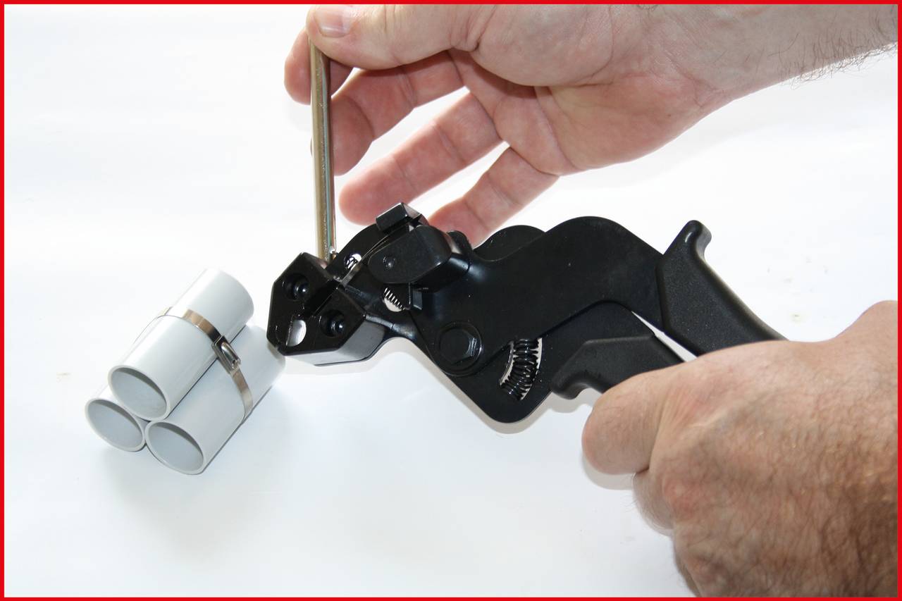 Eine Person zieht mit einem Werkzeug Kabelbinder an, um mehrere Rohre zusammenzubündeln.