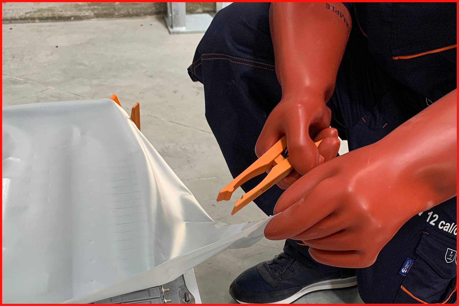 Eine Person in Schutzhandschuhen schneidet mit einer Schere eine Plastikfolie. Die Szene zeigt Vorsichtsmaßnahmen bei der Arbeit.