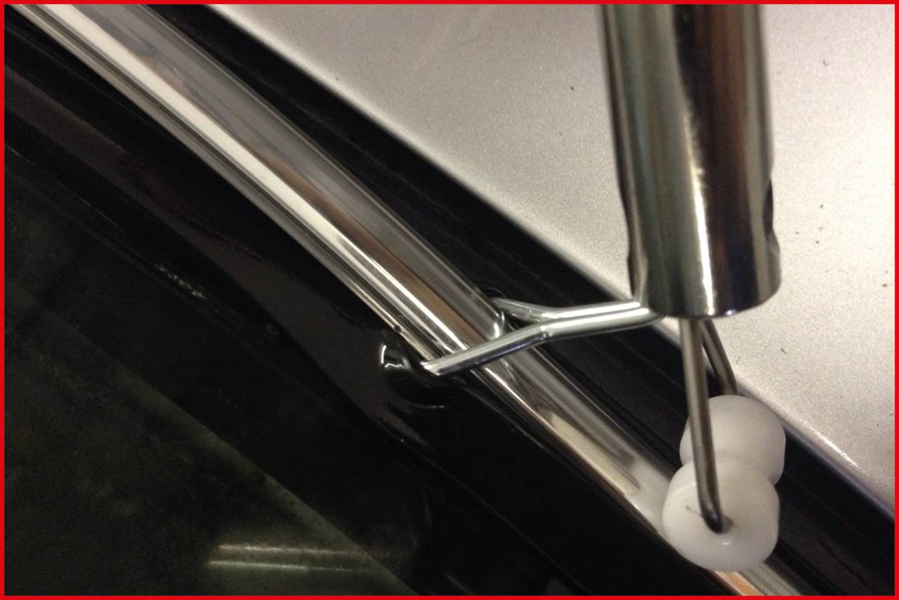 Ein Metallstab wird in die Verkleidung eines Autos eingesetzt, um die Innenverkleidung zu befestigen. Nahaufnahme der Dachkante.