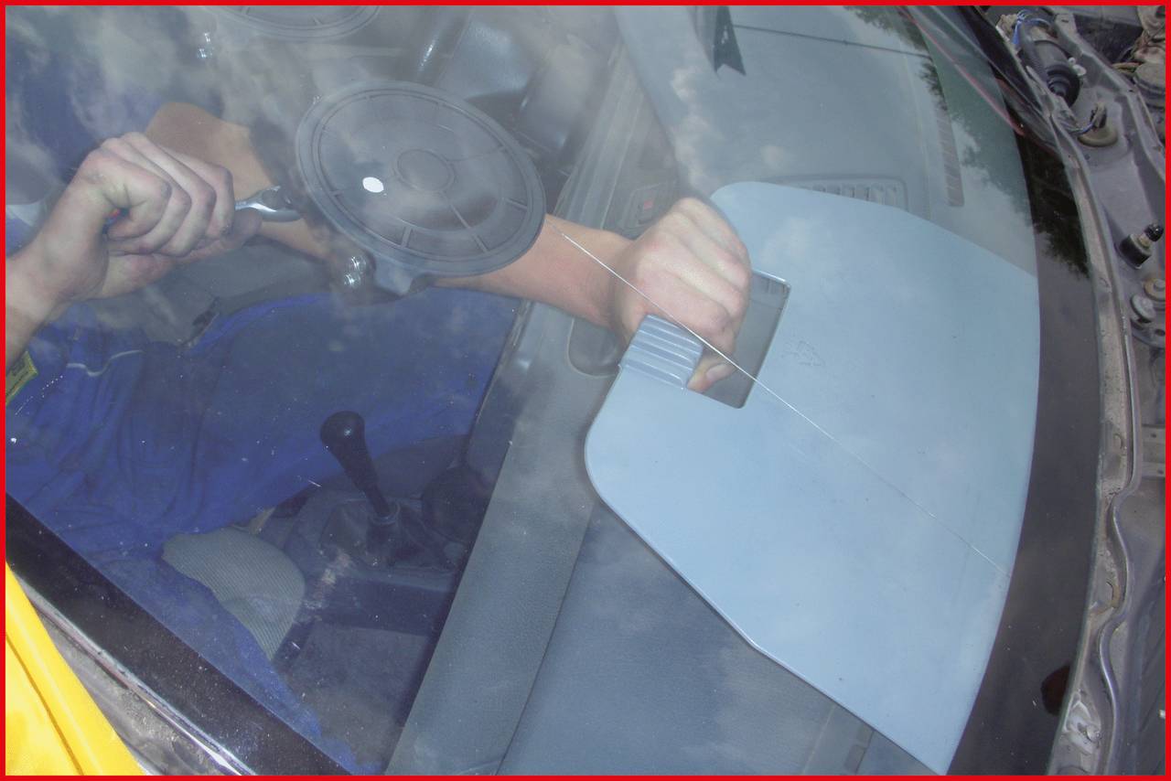 Person repariert Autowindschutzscheibe mit speziellem Werkzeug, um Riss zu beheben.