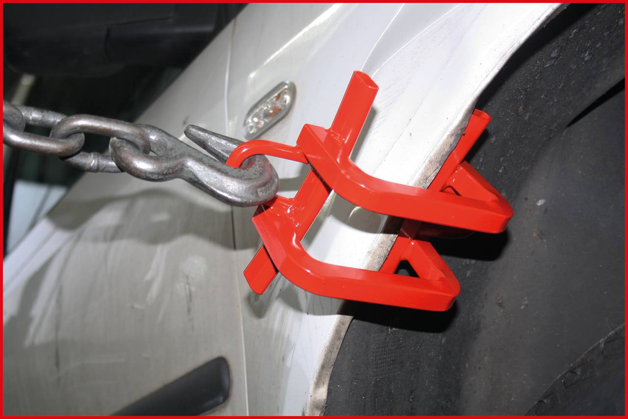 Rotes Blockiersystem an einem Autoreifen, verhindert Bewegung. Sicherheitsmaßnahme gegen unberechtigtes Parken oder Diebstahl.