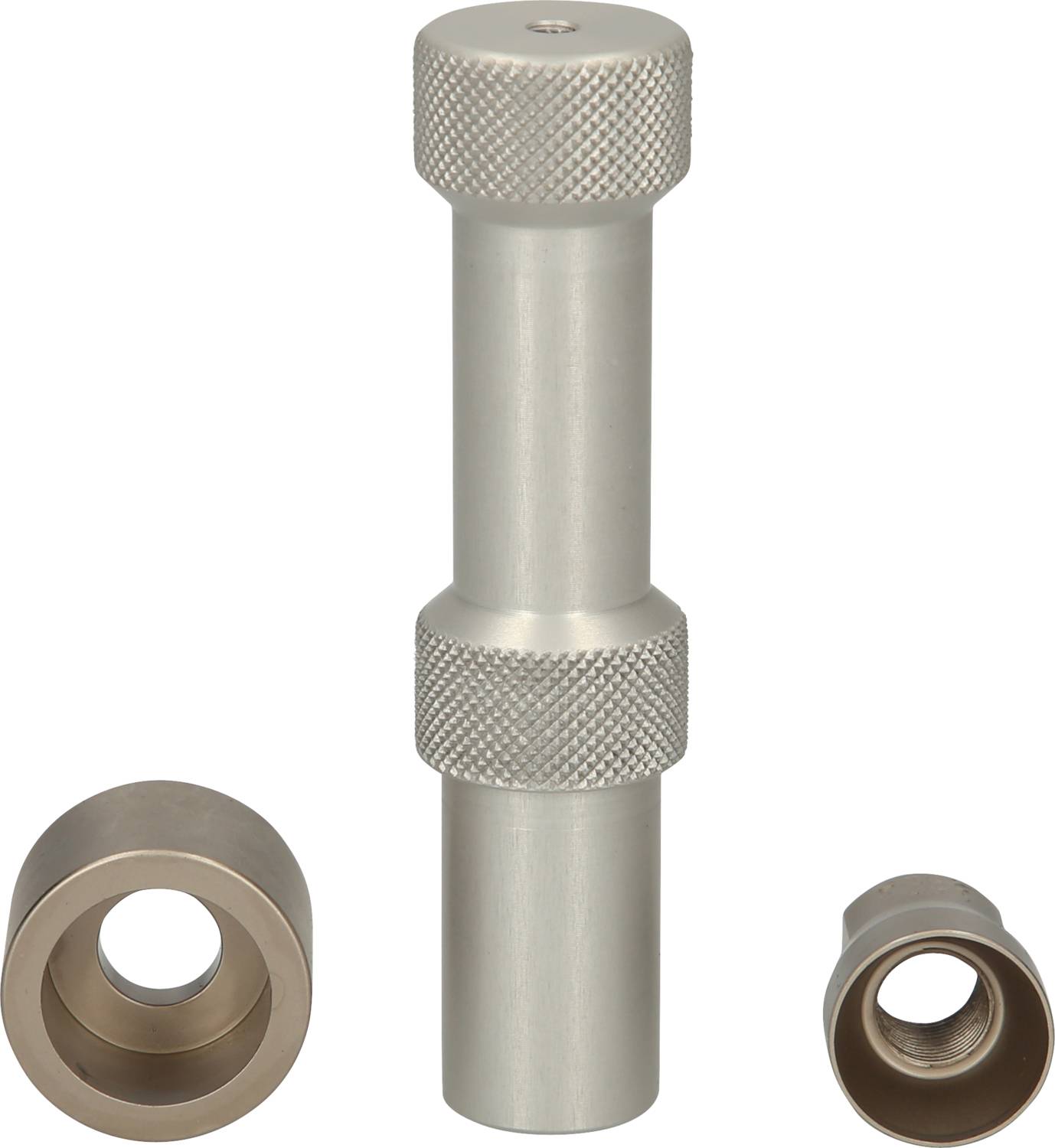 Ein zylindrisches Metallwerkzeug mit gerändeltem Griff. Daneben liegen zwei runde Metallaufsätze mit unterschiedlich großen Öffnungen.