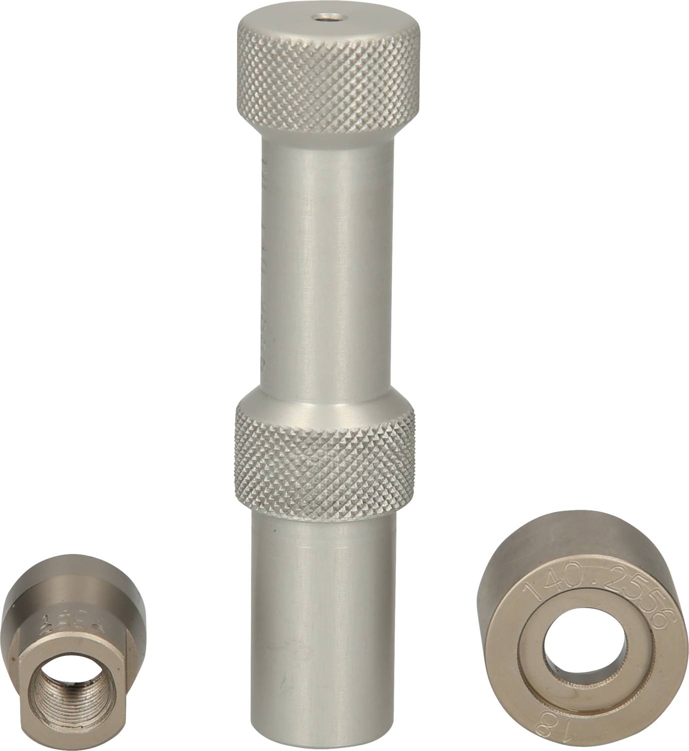Ein zylindrisches Metallwerkzeug mit gerändeltem Griff, flankiert von zwei runden Metalleinsätzen, unterschiedlicher Größe.