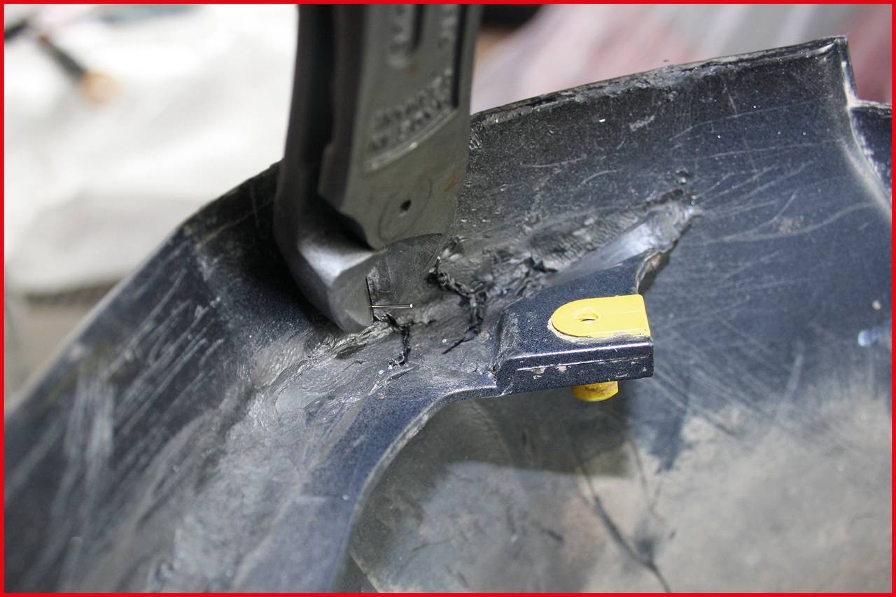 Ein schwarzes Kunststoffteil wird mit einem Messer bearbeitet. Die scharfe Klinge schneidet durch das Material, gelbes Detail sichtbar.