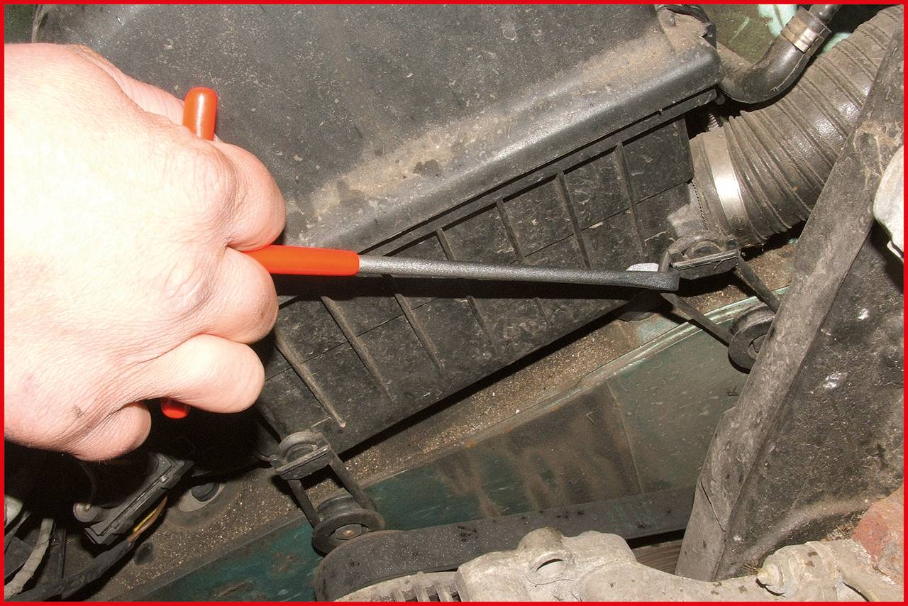 Eine Hand benutzt einen Schraubendreher, um die Teile eines Motors zu justieren. Im Hintergrund sind Motorenkomponenten sichtbar.