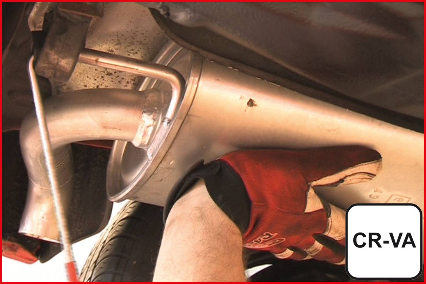 Eine Person montiert mit einer roten Arbeitshandschuh einen Schalldämpfer an einem Auto. Rechts unten ein Schild mit der Aufschrift 'CR-VA'.