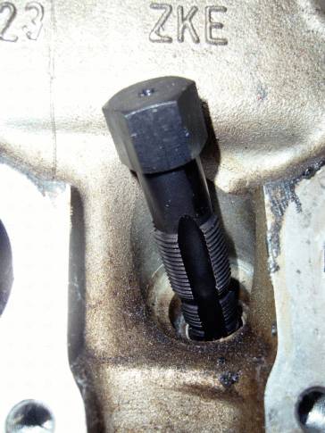 Bohrer in einem Gewindeloch eines Metallteils eingesetzt, mit der Gravur 'ZKE' oben sichtbar.