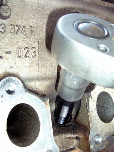 Nahaufnahme eines Zylinderkopfes mit einer installierten Ventilfeder und einem Schraubenschlüssel. Seriennummern sind erkennbar.