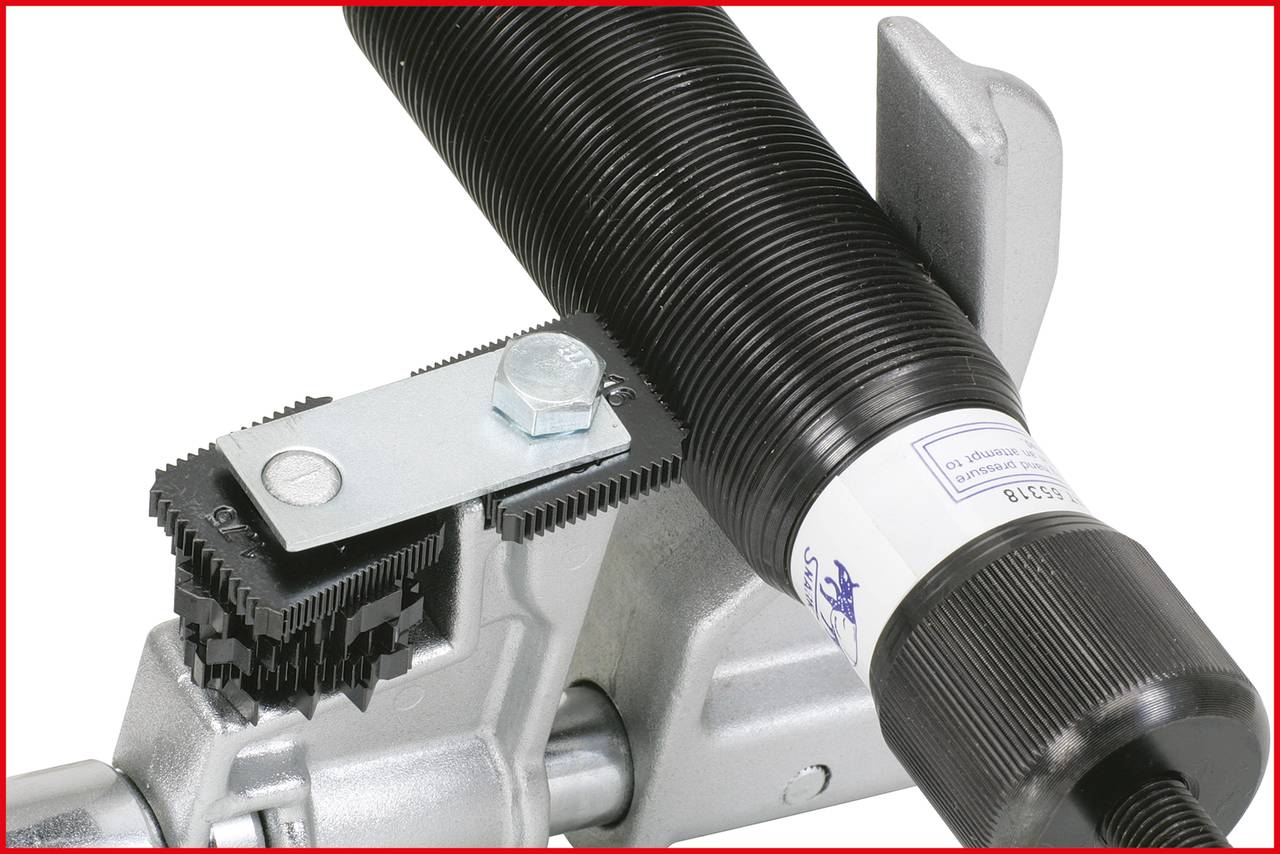 Ein Federsystem mit Spannmechanismus, bestehend aus einer großen Feder, einem Metallhaken und einer Schraube, montiert auf einem Metallrahmen.