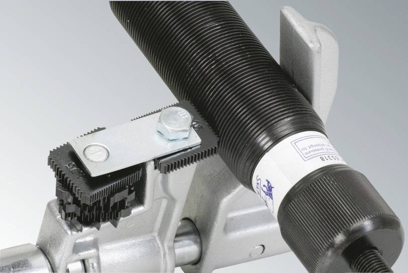 Ein Metallteil mit Schrauben und mechanischer Vorrichtung; möglicherweise Teil einer industriellen Maschine oder Ausrüstung.