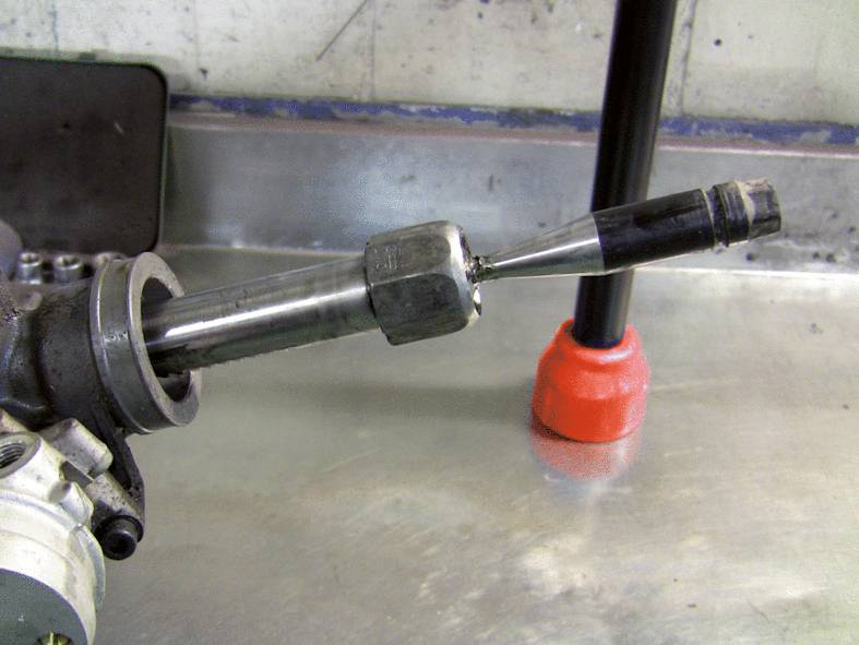 Ein Metallwerkzeug mit langem Schaft liegt auf einem Werkstatttisch. Es scheint Teil eines Maschinenbauteils zu sein.