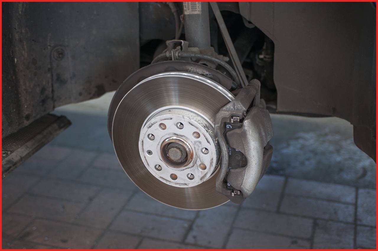 Die Nahaufnahme zeigt eine Autobremsanlage mit Bremsscheibe und Bremssattel. Sie ist unmontiert und ohne Reifen zu sehen.