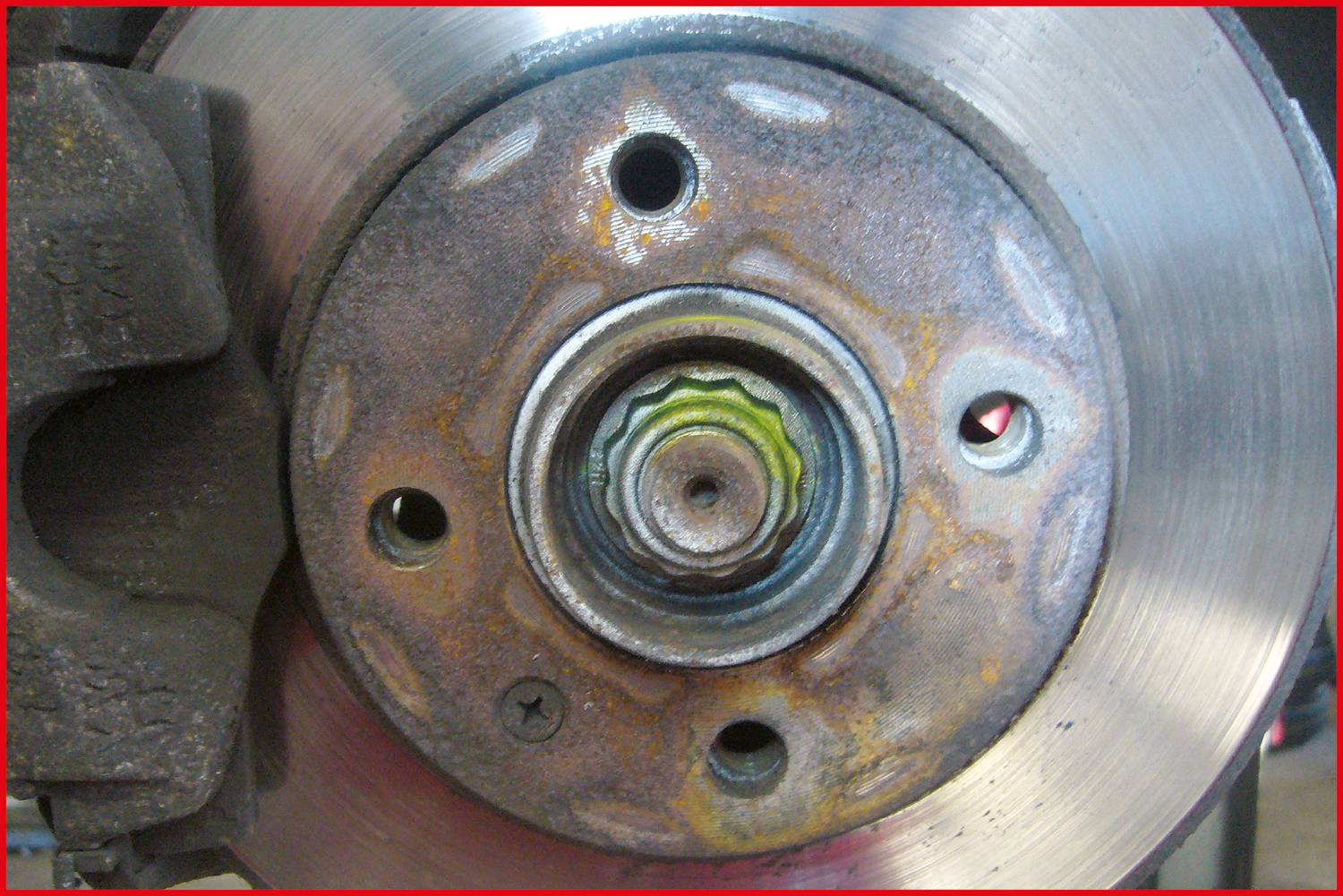 Nahaufnahme einer Bremsscheibe mit Rostansatz und sichtbarer Verzahnung. Links ist ein Bremssattel teilweise erkennbar.