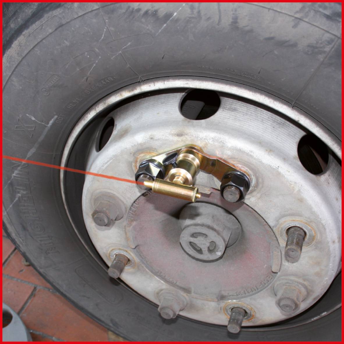 Nahaufnahme eines Lkw-Reifens mit einer roten Laserlihne, die zur Überprüfung der Achsausrichtung verwendet wird.