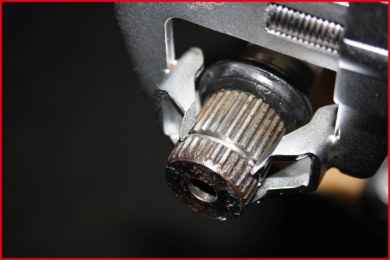 Nahaufnahme eines Werkzeugs, das an einem geriffelten Metallteil arbeitet. Fokus auf den Mechanismus, der das Teil greift und dreht.