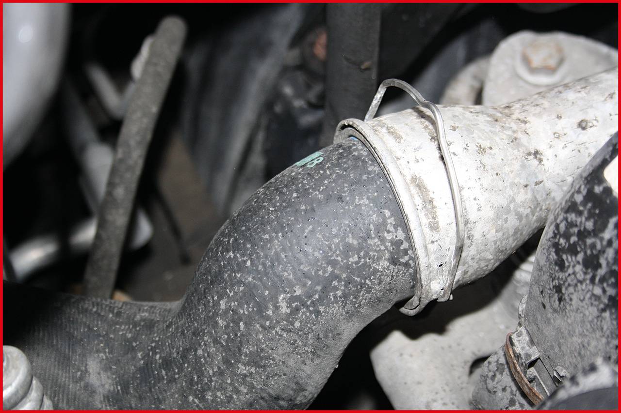 Ein Autofachwerkstück mit einem abgenutzten Schlauch und einer Klemme, die auf mögliche Wartungs- oder Reparaturbedürfnisse hinweist.