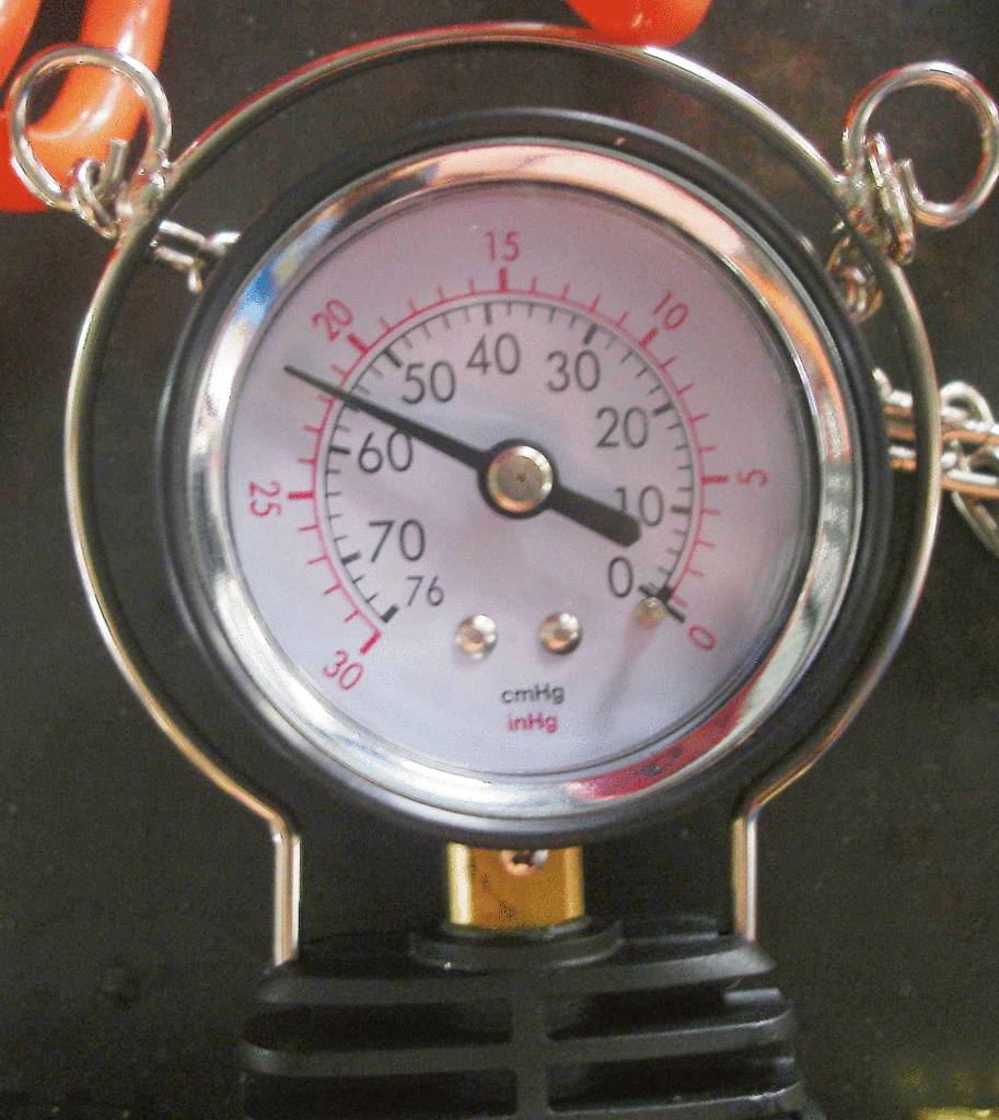 Manometeranzeige bei 60 cmHg. Instrument zur Messung des Drucks. Hintergrund unscharf, hauptsächlich schwarzes und silbernes Gehäuse.