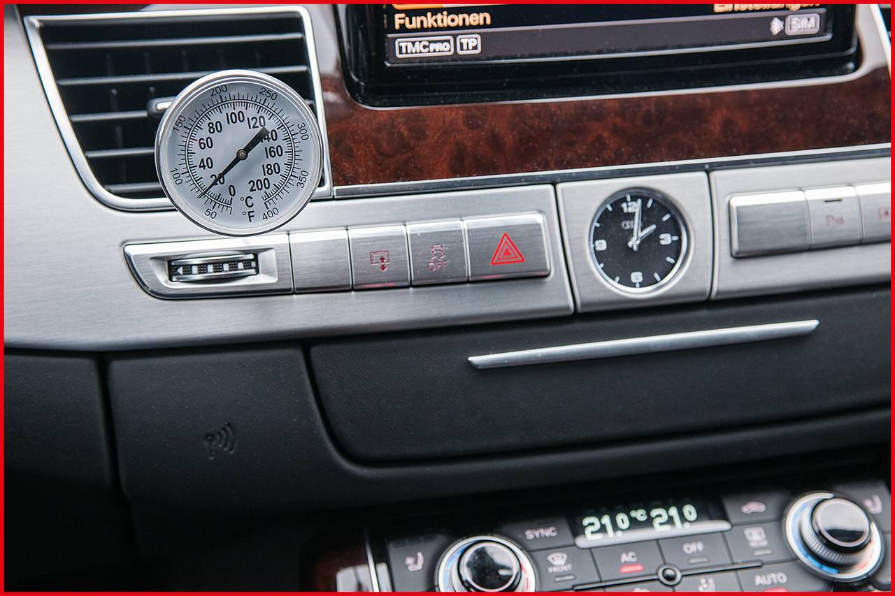 Innenraum eines Autos mit Armaturenbrett. Ein Temperaturanzeiger zeigt ca. 70 Grad an. Bedienungselemente sichtbar, inkl. Warnblinker.
